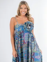 Vestido largo de algodón con estampado geométrico multicolor, corte cuadrado, breteles finos y falda amplia. Incluye aplique de flor desmontable.