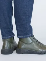 Botín de cuero color verde militar con cordones negros y suela de poliuretano.