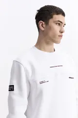 Buzo de algodón color celeste, con cuello redondo, puños y bolsillos laterales. Presenta estampados con texto en el pecho y un parche en la manga.