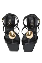 Sandalias de tacón alto PatBo modelo Zulu, color dorado metalizado, con tira en la puntera, diseño en T con aplique rígido en forma de concha marina, correa ajustable al tobillo y plantilla marrón.