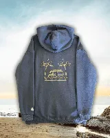 Hoodie de color azul con capucha y bolsillo frontal tipo canguro. Presenta un diseño estampado en la espalda con líneas finas que ilustran una camioneta tipo van, una tabla de surf y dos palmeras. Incluye un pequeño detalle bordado de la bandera de Uruguay en el puño de la manga.