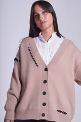 Cárdigan color beige con botones negros, escote en V y detalles de costuras bordadas en negro.