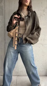 Campera tipo bomber de gamuza color verde, con diseño oversize, cuello camisero, cierre frontal y detalles de charreteras en los hombros.