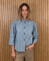 Camisa de algodón color blanco, con cuello alto con volados, mangas tres cuartos con detalles de bordado ingles y cierre frontal con botones de nácar.