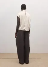 Blusa de seda color crema con cuello alto y detalle de pañuelo integrado en el escote. Presenta un diseño fluido y elegante de manga larga.