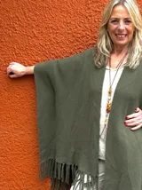 Capa estilo ruana verde militar con flecos en el ruedo y diseño abierto.