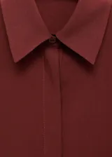 Camisa de lyocell color bordó, de diseño recto, manga larga con puños abotonados, cuello camisero y cierre delantero con botones ocultos.