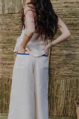 Pantalón palazzo color crudo con detalle de cinta bordada en los laterales y lazo en la cintura.