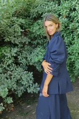 Blazer rojo de seda con cuello solapa, hombreras marcadas y un botón decorativo en forma de sol.