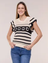 Buzo tejido en punto calado estilo crochet color beige con rayas horizontales negras y una franja central con motivos florales. Presenta cuello redondo, mangas cortas con volados y terminaciones en rib.