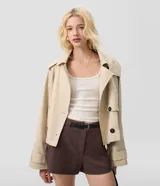Trench coat cropped beige con capucha, cierre cruzado con botones y mangas largas.