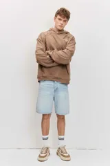 Canguro marrón con capucha, bolsillo frontal tipo kango y diseño oversize de corte relajado con mangas largas.