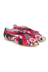 Zapatos tipo blucher de diseño artesanal, confeccionados en algodón con estampado floral multicolor sobre base negra. Presentan detalles en terciopelo color fresa, cierre con cordones rematados en borlas y suela de cuero.