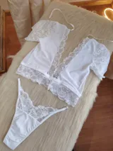 Conjunto de lencería blanco compuesto por un top de encaje con mangas cortas y una bombacha tipo colaless con detalles de encaje.