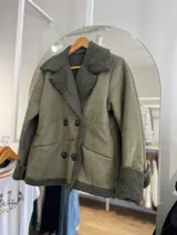 Chaqueta negra con forro tipo corderito, doble botonadura y cuello solapa.