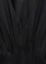 Vestido largo de color negro con cuello en pico y mangas cortas. Presenta un panel fruncido en la cintura que define la silueta y un diseño recto. Confeccionado en una mezcla de lino y ramio con forro de algodón.