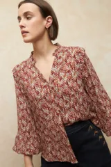 Camisa de manga larga con estampado geométrico en tonos azul y blanco, escote en V con detalle de volado en el cuello, cierre frontal con botones a tono y puños elásticos.