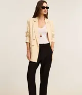 Pantalón de vestir negro, estilo carrot (holgado en cadera y ajustado en tobillo), de cintura alta con trabillas y cierre tradicional. Presenta recortes verticales con costura aparente en el frente.