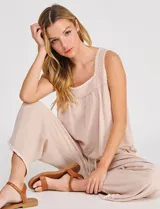 Pantalón palazzo de lino color beige, de tiro alto y silueta suelta, con cintura elastizada y cordón de ajuste. Cuenta con detalles de ribetes bordados festoneados en contraste en los bolsillos y en el ruedo.