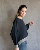 Buzo tostado de corte holgado con cuello redondo y manga larga. Presenta una estrella blanca estampada en la espalda y ribete marrón en cuello y ruedo.