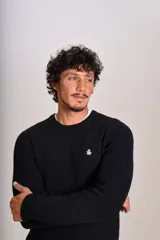Sweater de punto con textura acanalada, color negro, de cuello redondo y manga larga. Presenta un pequeño logo bordado en el pecho.