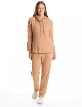 Buzo de tejido suave con cuello volcado ajustable mediante cordones con punteras metálicas. Presenta mangas largas con puños decorados con botones metálicos, hombros caídos y ruedo redondeado con aberturas laterales.