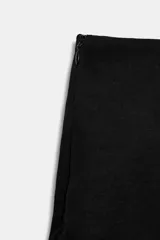 Falda pantalón corta de tiro medio, color negro, con diseño cruzado y detalle de lazada en el delantero.