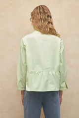 Camisa blanca de manga larga y cuello mao, estilo victoriano. Cuenta con un botón plateado a la vista.