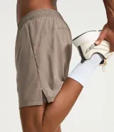 Bermuda deportiva color bordó, confeccionada en poliéster, con cintura elástica, cordón interno ajustable y short de compresión incorporado.