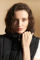 Chaleco acolchado de nylon color negro, con diseño capitoneado, capucha integrada y cierre frontal con tirador metálico.