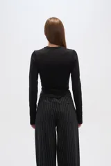 Top negro de manga larga, al cuerpo y cuello a la base.