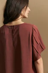 Top de color azul, con escote redondo a la base y mangas cortas amplias con caída fluida. Presenta una silueta relajada y un diseño minimalista.