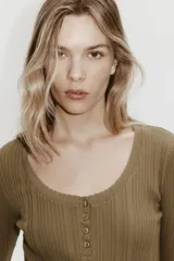 Top de manga larga en punto acanalado de algodón con diseño pointelle, escote en U con ribete festoneado y tapeta con botones frontales.