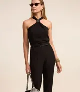 Pantalón de sastrería corte carrot, color beige, con cintura alta, pinzas frontales y cinturón fino incorporado con hebilla metálica.