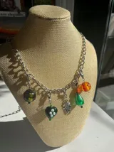 Collar plateado con cadena de eslabones y dijes colgantes con forma de hojas y árbol.