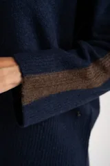 Sweater de tejido de punto con calce oversize, color azul marino con detalles en color marrón en las mangas y cuello. Presenta un diseño de manga larga y puños y ruedo acanalados.
