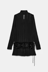 Vestido corto de viscosa color negro con cuello perkins y manga larga. Presenta un fajín de terciopelo integrado con bordados a tono y detalle de lazadas laterales.
