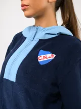 Buzo de micropolar color bordó con capucha, cierre frontal parcial y detalles en color crema. Presenta el logo de Umbro y el escudo del Club Nacional de Football bordados en el frente.