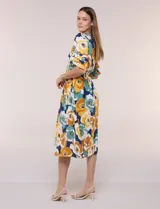 Vestido midi de calce holgado y caída fluida con escote en V cruzado, cintura elastizada fruncida y mangas cortas con volados superpuestos. Cuenta con un diseño estampado de flores grandes en tonos amarillo, blanco, azul marino y verde.