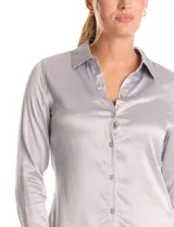 Camisa de satén color verde oliva, con cuello clásico, cierre frontal con botones metálicos y mangas largas con puños abotonados.