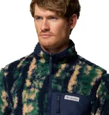 Campera polar de textura tipo corderito con estampado camuflado en tonos verde, azul marino y beige. Presenta cierre frontal completo, cuello alto y un bolsillo frontal en el pecho con cierre y parche de la marca.