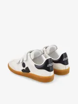Zapatillas urbanas de cuero blanco con detalles en negro, ajuste con tiras de velcro y suela de goma color caramelo.