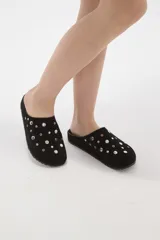 Suecos tipo zueco color negro con acabado de gamuza, decorados con tachas metálicas plateadas circulares. Poseen suela plana y diseño abierto en el talón.