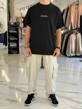 Remera oversize negra con estampa gráfica en la espalda que incluye un tiburón naranja, texto tipográfico y detalles en blanco.