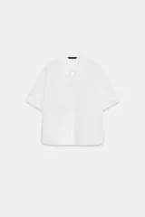 Camisa blanca de manga corta con solapa y cierre frontal con botones ocultos.