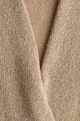 Top de punto sin mangas, color beige, con diseño cruzado en el frente, escote en V pronunciado y pliegues en los hombros. Presenta un dobladillo acanalado.