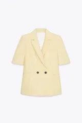 Blazer color amarillo pastel con textura, cuello solapa, manga corta con hombreras, bolsillos de vivo en delantero, forro interior y cierre frontal cruzado con botones.