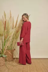Conjunto de dos piezas color bordó, compuesto por una blusa de manga 3/4 y cuello redondo, y un pantalón de corte recto. Ambas prendas tienen una textura plisada.