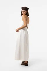 Vestido largo blanco con escote strapless y cuerpo fruncido. Posee falda amplia y fluida con bolsillos.