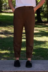 Pantalón de corte relajado con inspiración sastrera, color marrón, de tiro medio-alto. Presenta cintura con pasacintos, bolsillos laterales y un diseño que se ajusta en el tobillo con pinzas, logrando una silueta moderna.